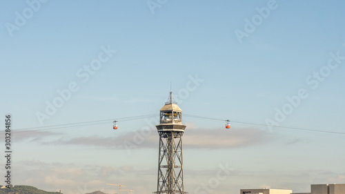 historic cable car cabins approaching  steel towers, harbor and Barcelona city, spain
