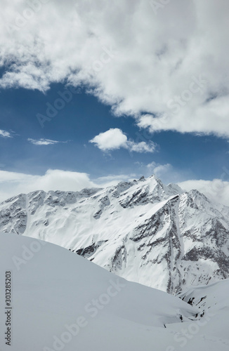 Snowy mountains and clouds in the sky on a sunny day