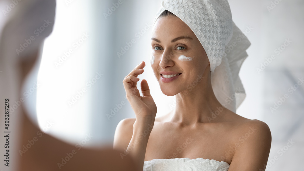 Smiling pretty lady put moisturizing facial cream look in mirror - obrazy, fototapety, plakaty 