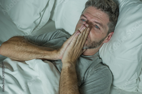 Canvas Print dramatic portrait of stressed and frustrated man in bed awake at night suffering