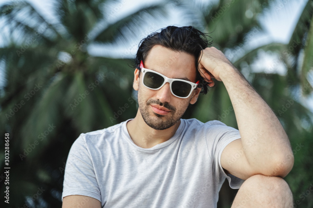 Stylish sexy young brunette man with a beard in sunglasses, closeup portrait outdoor, beauty and fashion Stylish sexy young brunette man with a beard in sunglasses, closeup portrait outdoor, beauty and fashion