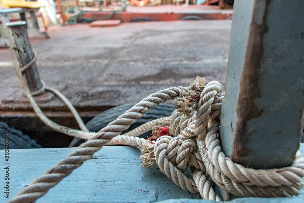 A boat at the harbor pontoon, close-up view of the rope tied at bollard. Boat moored at the pier.