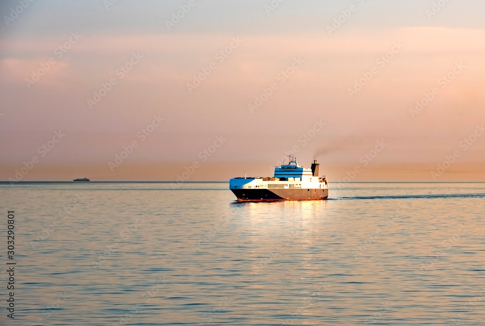 Container bulk carrier ship in a clam sea at sunset