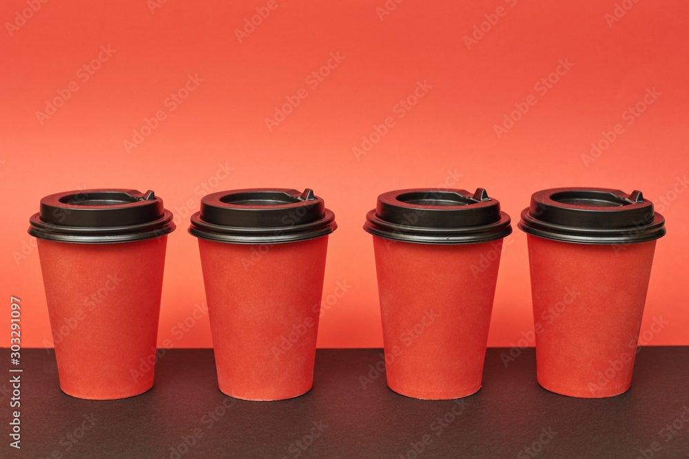 Red disposable paper cup for takeaway drinks. Mockup red paper cup on red and black background. Red disposable paper cup for takeaway drinks. Mockup red paper cup on red and black background.