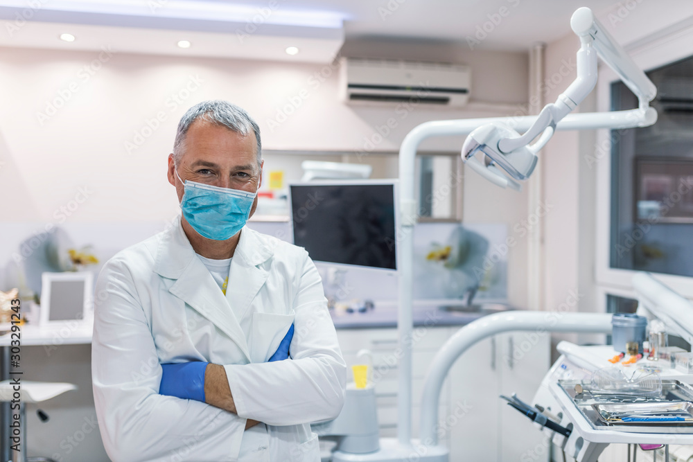 Male dentist standing with his hands crossed and looking at camera Male dentist standing with his hands crossed and looking at camera