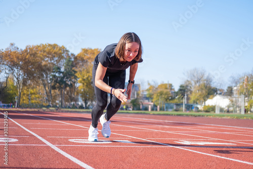 Young female runner training in summer day outdoors on the studium 