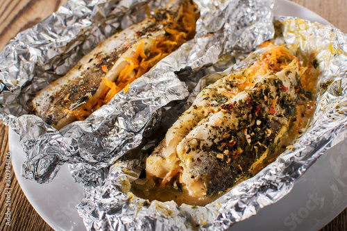 Grilled trout with herbs and lemon on aluminium foil photo