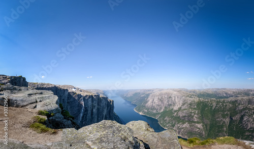 Panoramic view of Lysefjord high cliff with girl hiker standing on rock plateau Norway