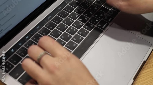 Female hands are typing on a laptop in an office. Russian keyboard