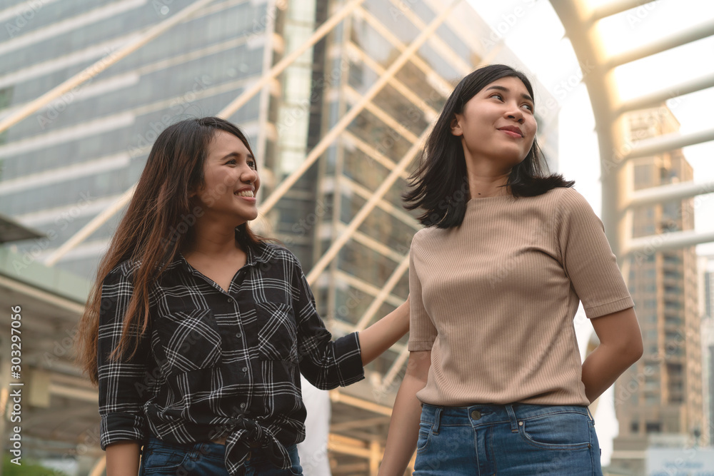 Young diverse pretty Asian girlfriends downtown in urban city - Mixed race girls walking together smiling - Lifestyle social time with millennial best friends - Friendship, hang out and ethnic concept