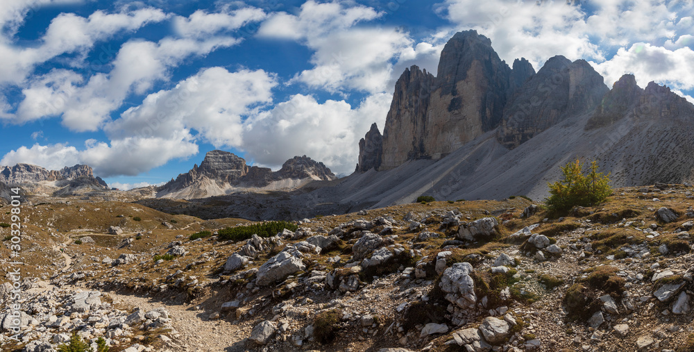 View of the mountains and valleys around Tre Cime in the Italian Dolomites. The photo has a nice background with blue sky and white clouds.