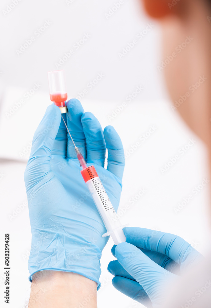 Doctor holds a syringe with red liquid in his hands (with white background, vertical, 6405) Doctor holds a syringe with red liquid in his hands (with white background, vertical, 6405)