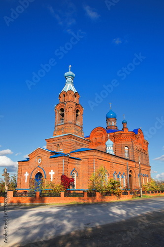The building of a religious temple made of red brick against the blue sky. View of the building of a rural church in the sun.