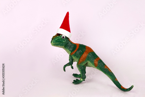 funny green dinosaur toy in little santa claus hat © dvulikaia