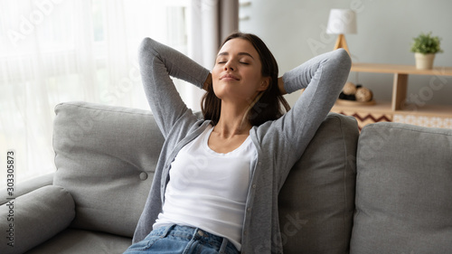 Obraz na plátne Relaxed serene young woman lounge on comfortable sofa at home