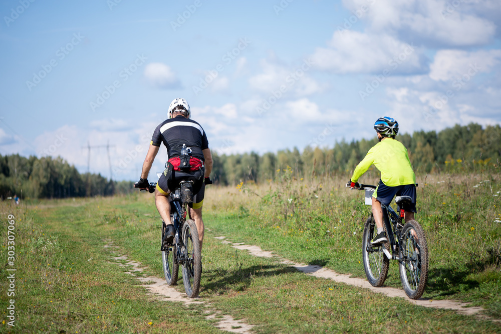 two cyclists ride a country road