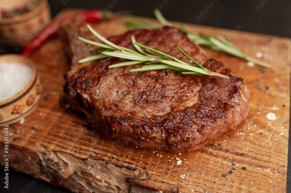 Grilled beef steak with spices on a stone background Grilled beef steak with spices on a stone background