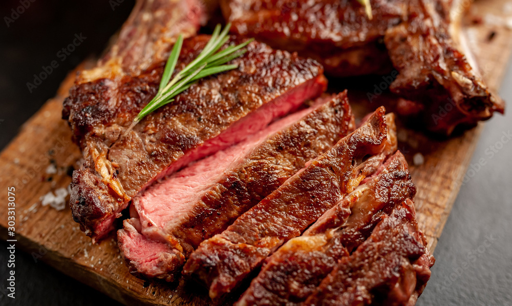 Grilled beef steak with spices on a stone background Grilled beef steak with spices on a stone background