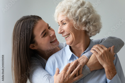 Smiling young woman granddaughter embracing happy old granny or mom