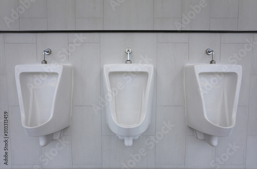White urinals in the men's bathroom of interior decoration.