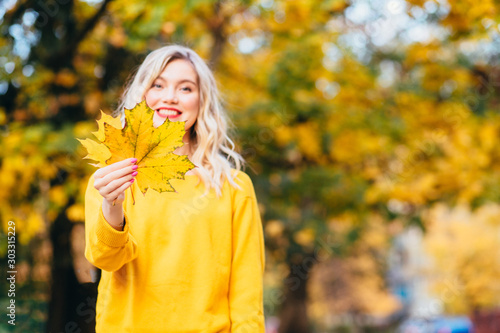 Autumn woman. Autumn Clothing and color trends. Smiling funny girl playing with leaves. Autumn woman. Beautiful autumn woman on fall nature background