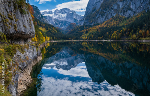 Peaceful autumn Alps mountain lake with clear transparent water and reflections. Gosauseen or Vorderer Gosausee lake, Upper Austria. Dachstein summit and glacier in far.