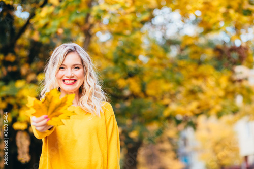 Autumn woman. Autumn Clothing and color trends. Smiling funny girl playing with leaves. Autumn woman. Beautiful autumn woman on fall nature background
