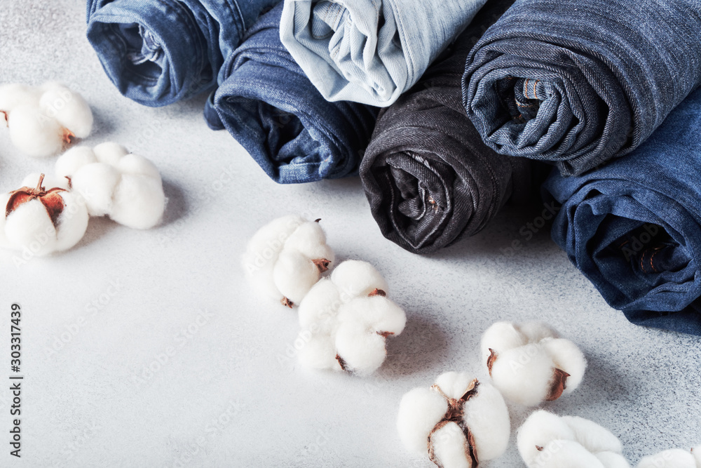 Rolled jeans and cotton flowers on light background - obrazy, fototapety, plakaty 