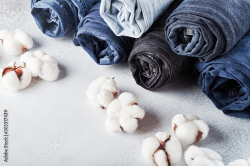 Rolled jeans and cotton flowers on light background