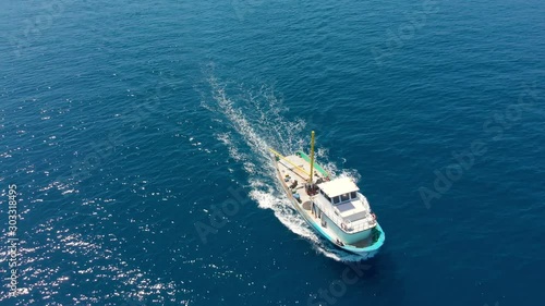 A small fishing boat in the afternoon goes at full speed into the open sea to search and catch salmon against the backdrop of the mountain. Fishing in the ocean, shooting from a helicopter.