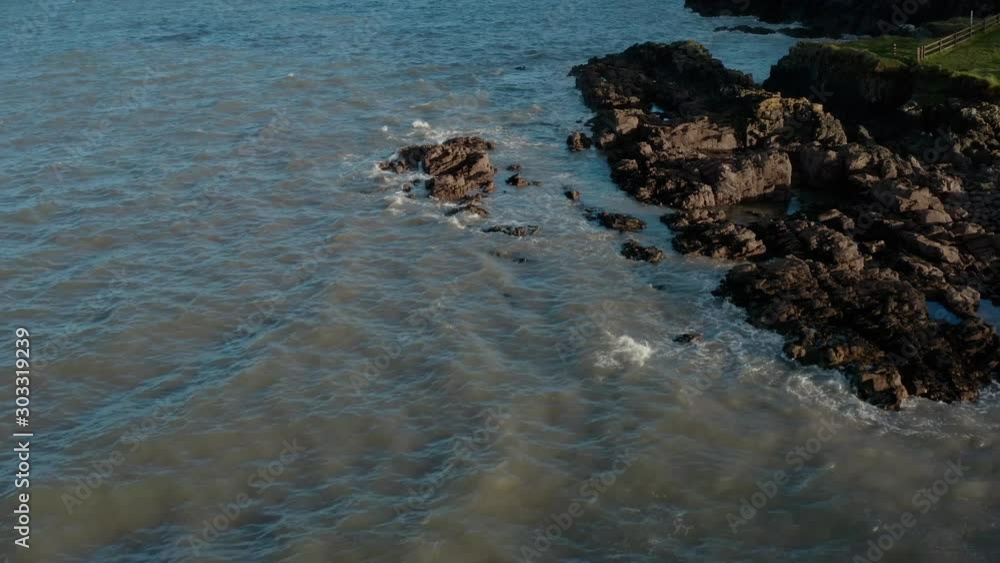 Zoom out Aerial Shot of South Ireland Seashore during the day. Waves crashing into rocks. Zoom out Aerial Shot of South Ireland Seashore during the day. Waves crashing into rocks.