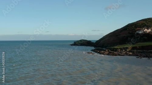 Slow Aerial Dolly Shot of South Ireland seashore during the day. Waves in ocean are calm. photo