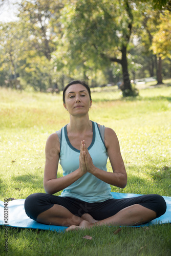 Healthy middle aged woman doing yoga in the park