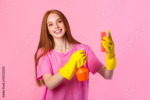 beautiful young woman with red hair in yellow rubber gloves on a pink background with