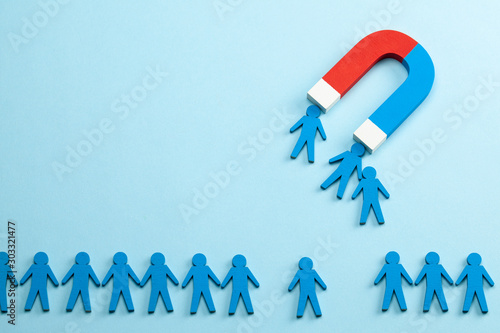 Personnel recruitment and a magnet attracts good employee leaders. Blue background photo