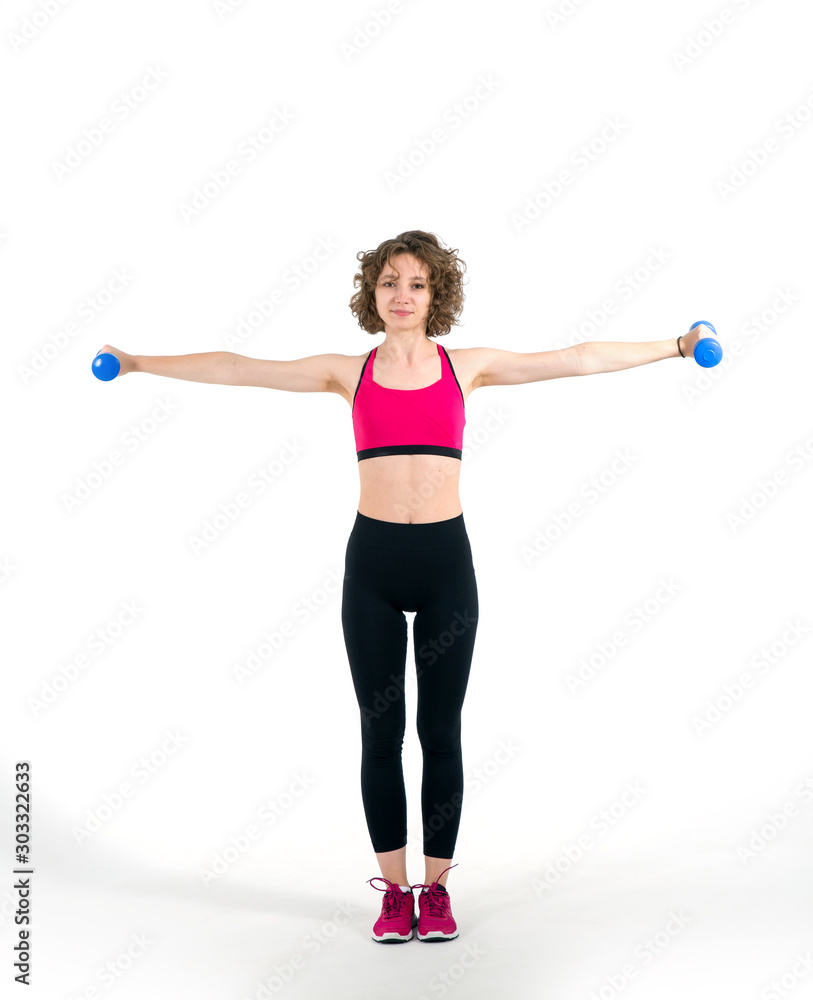 Curly young woman with dumbbells in hands, standing full length on a white background. Girl is engaged in fitness. Curly young woman with dumbbells in hands, standing full length on a white background. Girl is engaged in fitness.