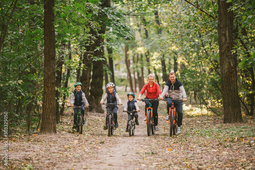 parents and kids cycling on forest trail. Young family cycling in autumn park. Family mountain biking on forest. Theme family active sports outdoor recreation. Family Cycling Through Fall Woodland
