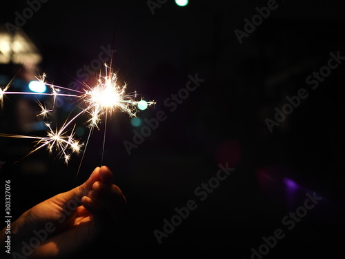 Hand holding a burning sparkler firework, Happy new year and Merry christmas concept, Happy holidays, Female hand holding a burning sparkler, Abstract blurred of Sparklers for celebration.