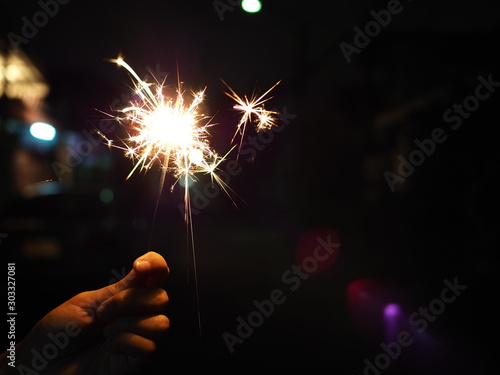 Hand holding a burning sparkler firework, Happy new year and Merry christmas concept, Happy holidays, Female hand holding a burning sparkler, Abstract blurred of Sparklers for celebration.