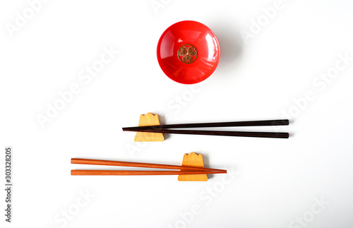 Wooden chopsticks and red cups on a white table top view