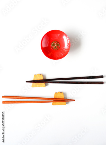 Wooden chopsticks and red cups on a white table top view