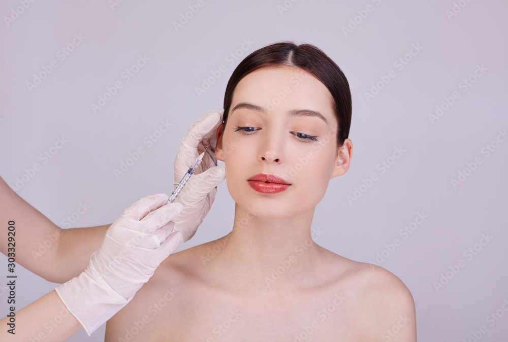 Beautician makes procedures for face injections of a young woman.