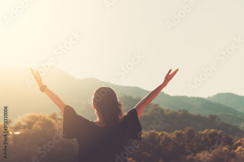 Copy space of woman rise hand up on top of mountain and sunset sky abstract background.