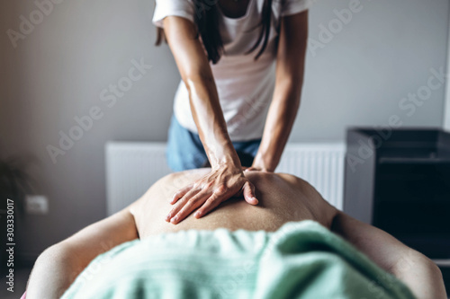 A woman physiotherapist doing back massage for a man in the medical office. Closeup of hands doing massage