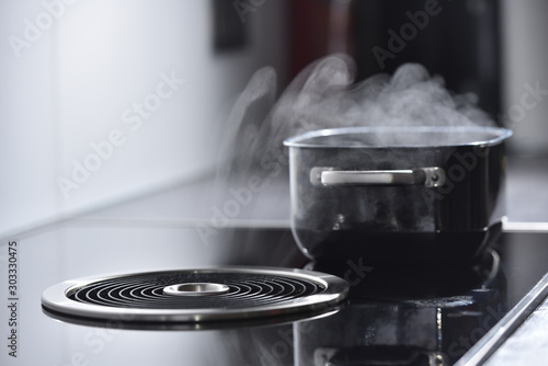 Fotografija Modern electric induction cooker with built-in ventilation and extractor hood which draws steam from boiling water in a pan