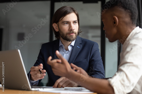 Focused businessman listening to young african american employee. photo