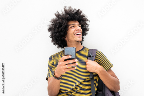 happy young guy with bag and cellphone smiling on isolated white background
