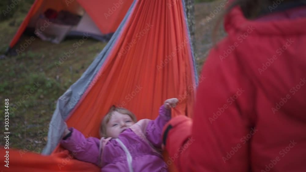 baby swinging and hiding in hammock in forest camping. mom custody. hiking, travel, family, child foster, bonding concept. parent playing with daughter outside. baby swinging and hiding in hammock in forest camping. mom custody. hiking, travel, family, child foster, bonding concept. parent playing with daughter outside.
