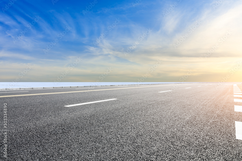 Fototapeta premium Country road and farmland snow scene at sunset