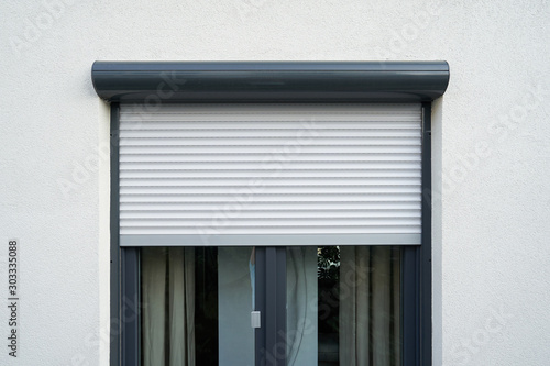 Light roller shutter curtains mounted on a dark window photo